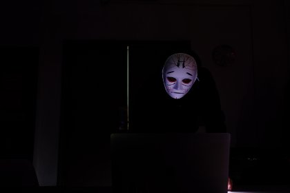 Masked performer at a laptop